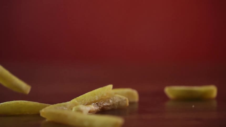 French fries falling onto a table with a red background