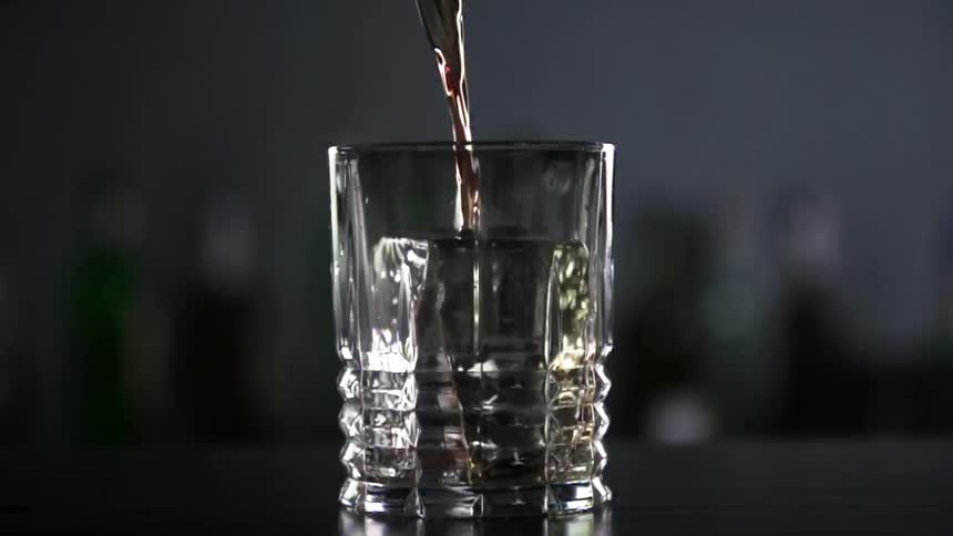 An alcoholic beverage  being poured into a glass on a table
