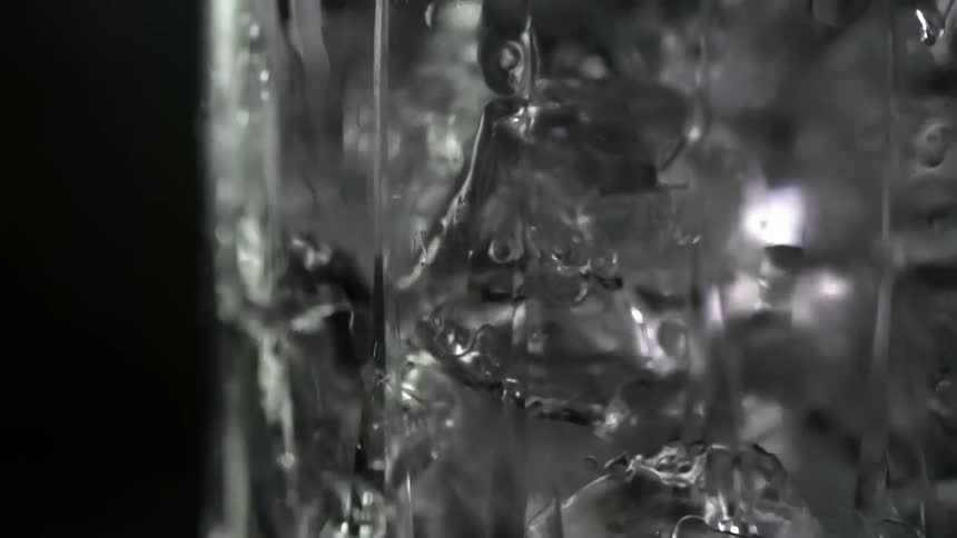 Ice cubes falling inside a glass against a black background