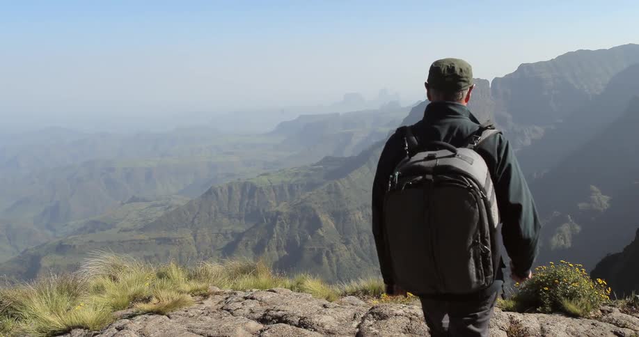 A man is hikes over to the edge of a cliff