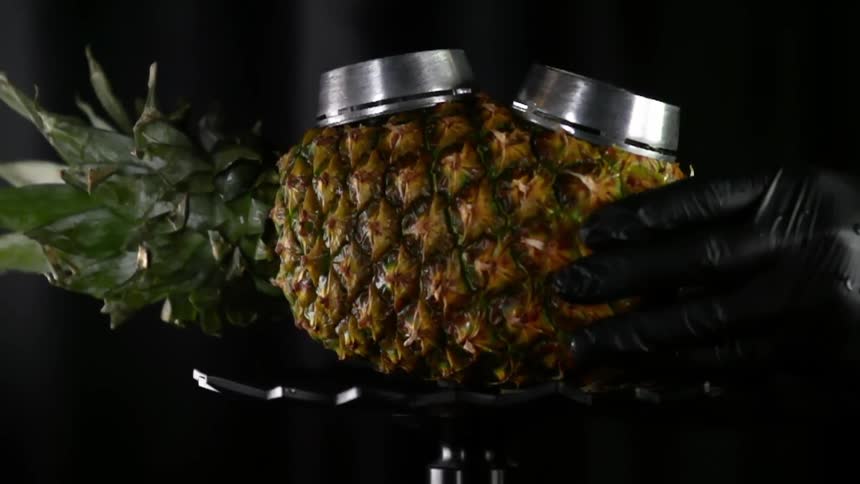 A person places a pineapple used as bowl on top of a stem