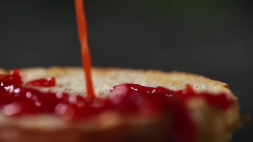 Ketchup squirting over a toasted bun