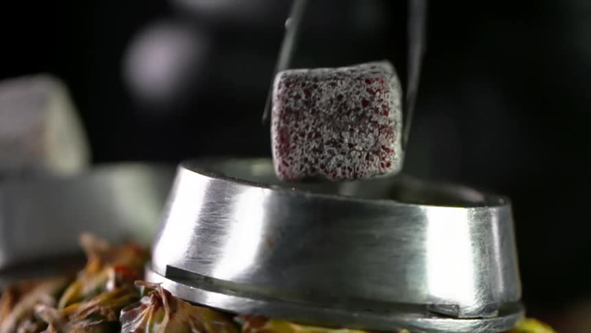 A charcoal cube is dropped into a metal ring