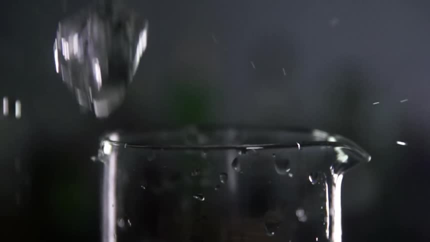 Ice cubes fall inside and around a glass jar