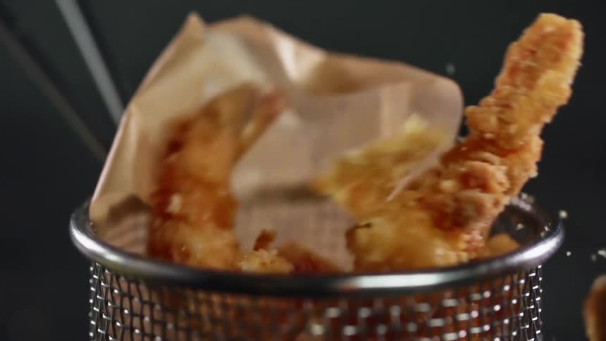 Fried shrimp nugget falling into a basket