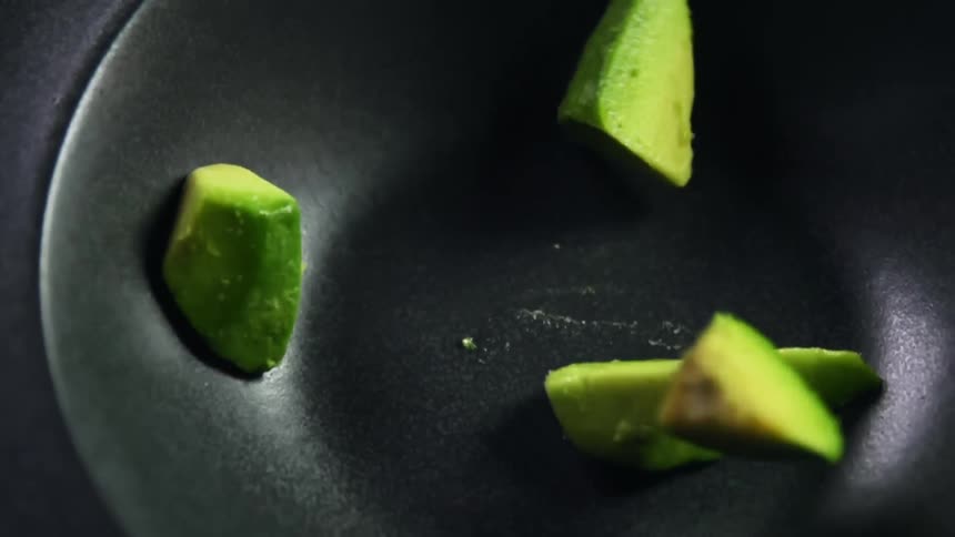 Chunks of avocado being dropped into a bowl