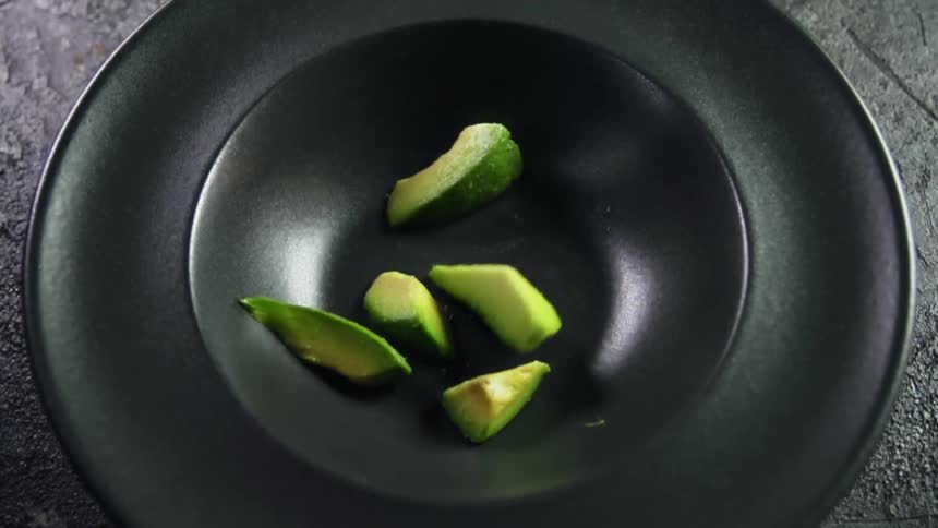 Sliced avocado falling into a bowl