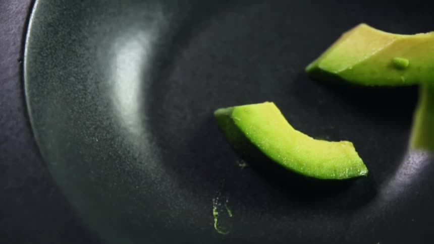 Chunks of avocado being dropped into a bowl