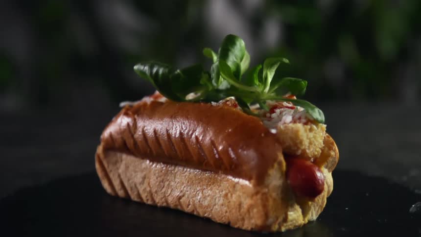 Green garnish falls onto a cooked hot dog