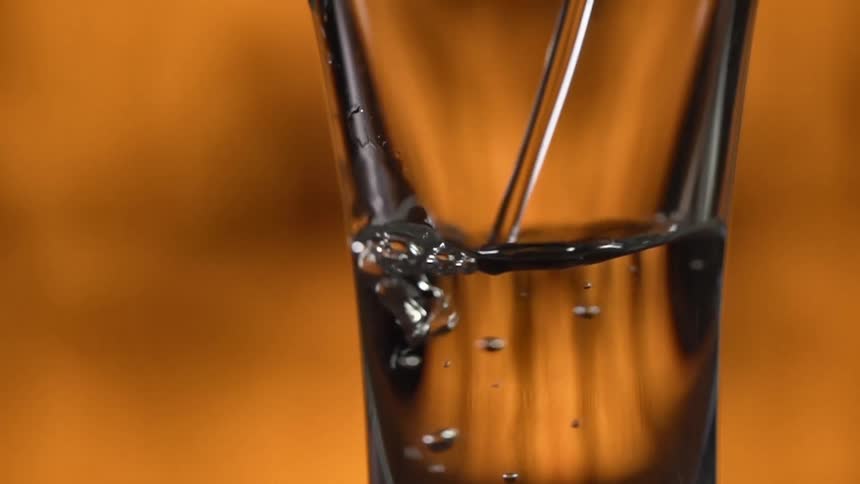 A liquid being poured into a glass with bubbles