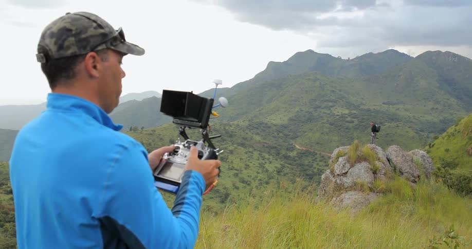 A man is using a controller while standing on a mountain