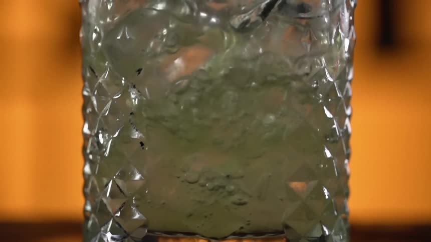 A liquid being poured into a glass with ice
