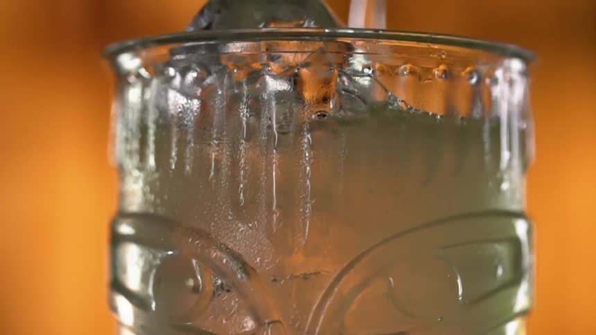 Liquid pours onto ice into glass decorated with carved eyes