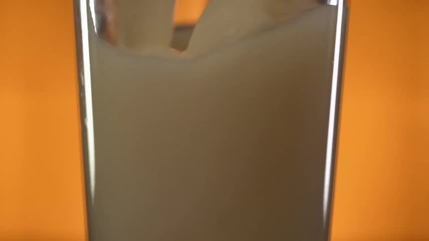 A thick yellowish white liquid is being poured into a glass in a bar