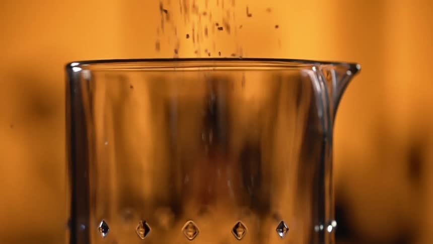 Sesame seeds being poured into a glass jug