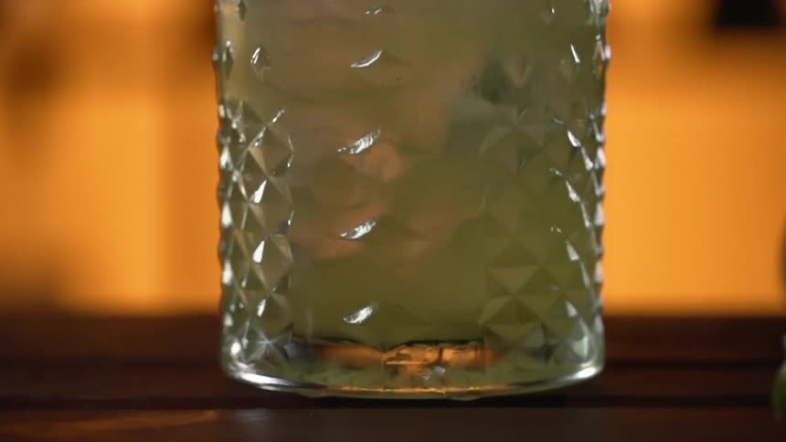 A spoon stirs ice and ingredients in a cocktail