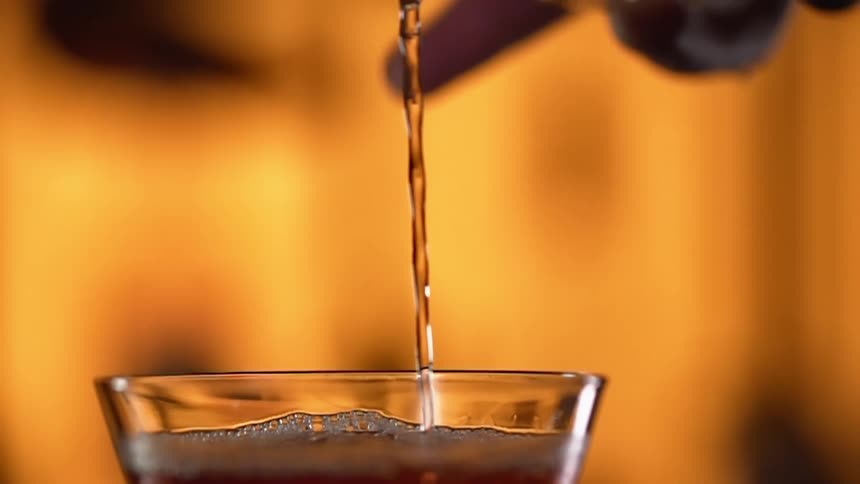 An alcoholic beverage is poured into a glass