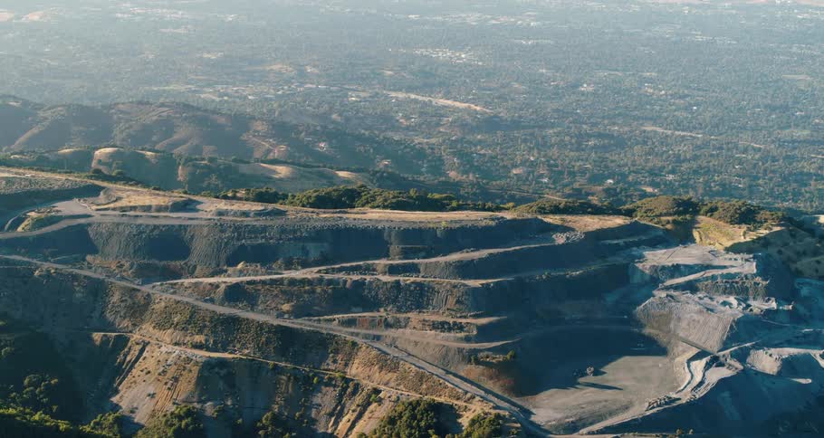 Aerial view of an open mine quarry on the side of a mountain near a lake