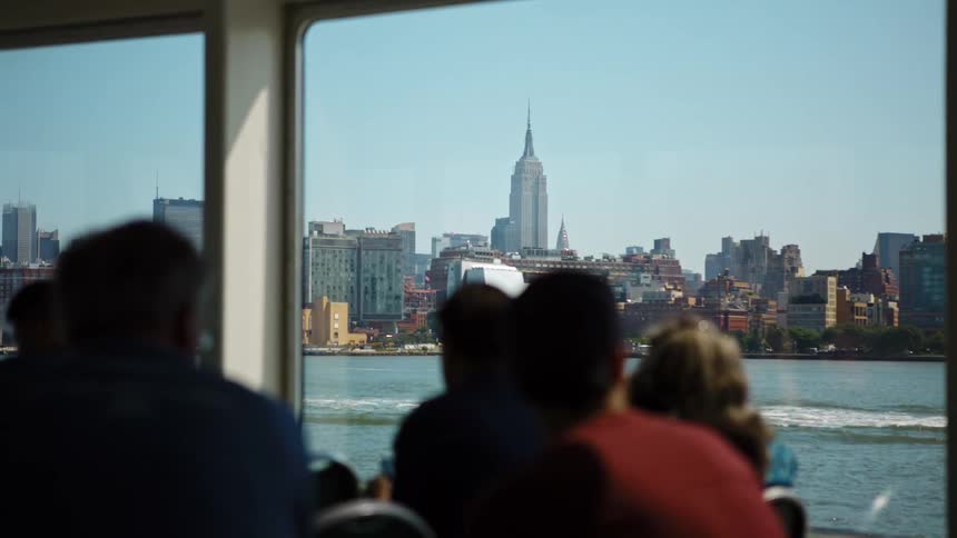 People sitting in a boat look across the water at the skyline