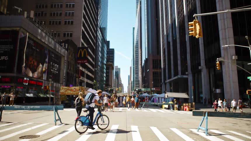 People cross the intersection and cars drive past