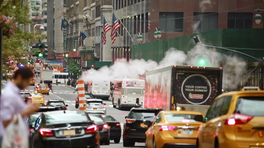 A man looks at heavy traffic on a city street before jaywalking