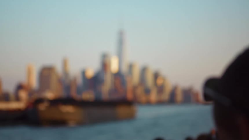 People photographing new york city skyline with a phone from a boat in the river