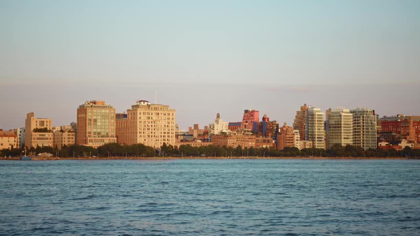 Several tall buildings in an urban are stand tall along a city coastline