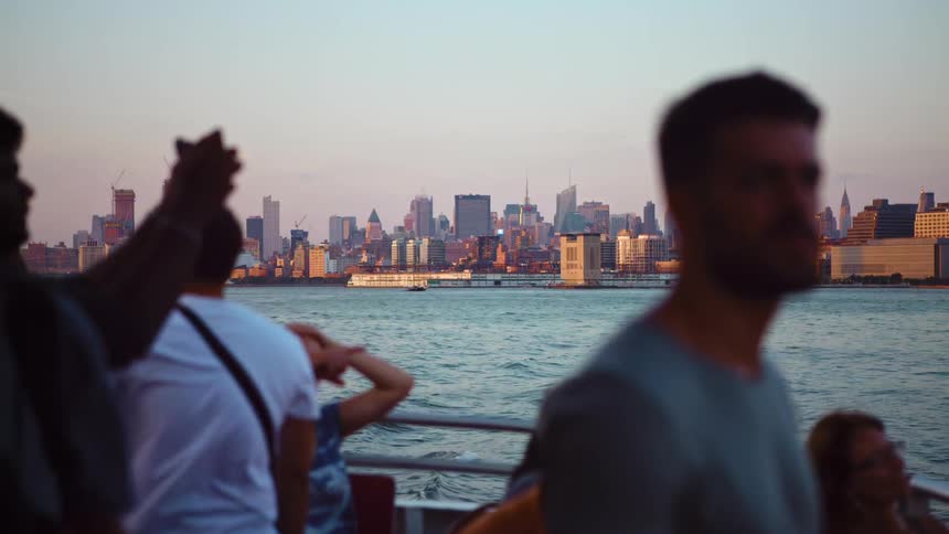 A group of tourists ride a ship on the ocean outside of a metropolis