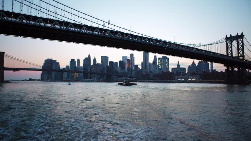 A river with bridges and boats with the city skyline with buildings and skyscrapers in the background