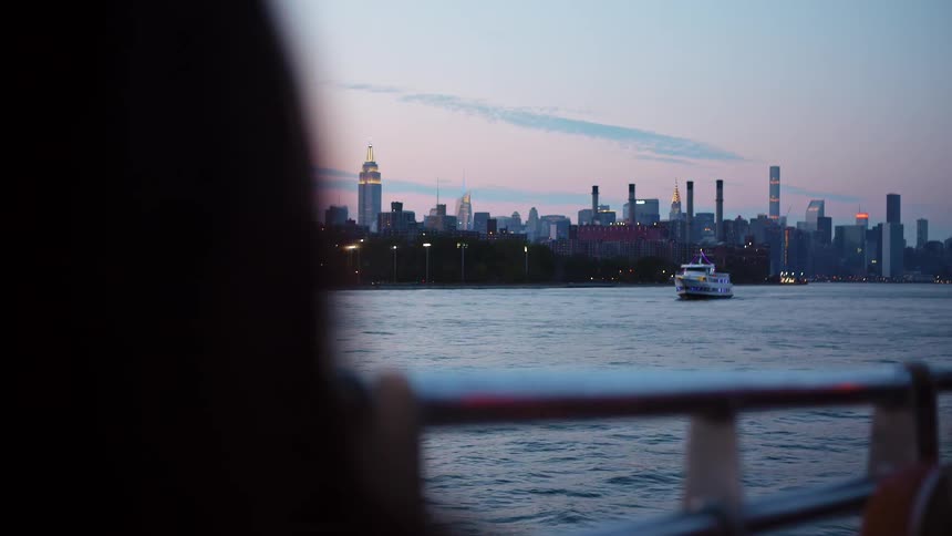 People ride on the boat at sunset past the city
