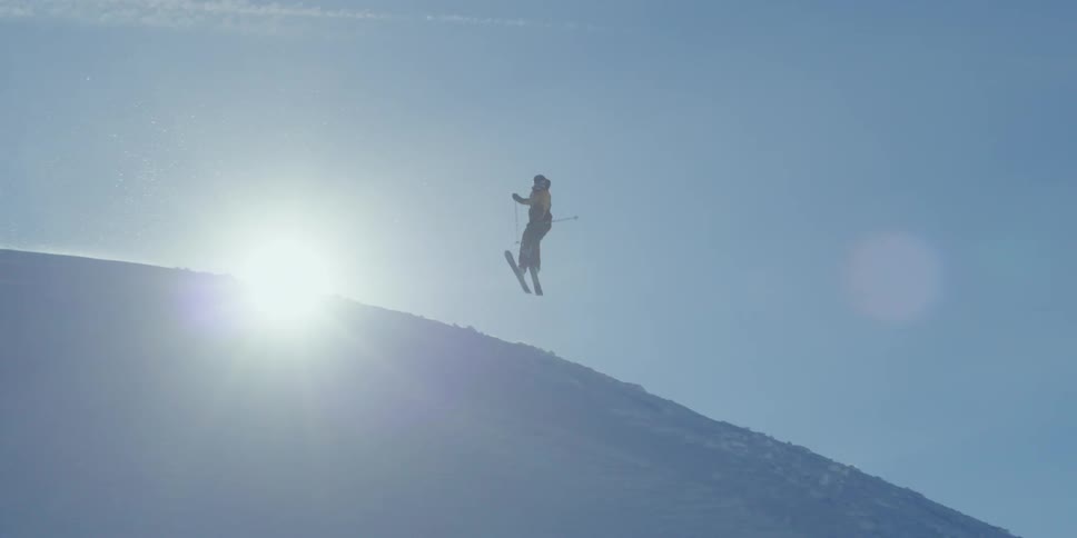 Backlit backcountry skier hits a jump and spins