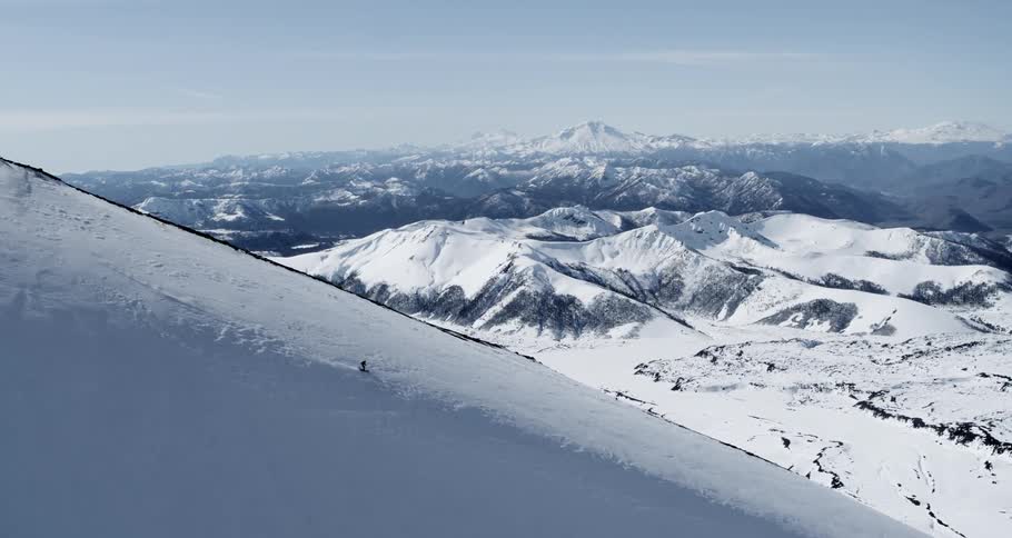 Aerial of a skier on a ridge in front of a massive volcano vista
