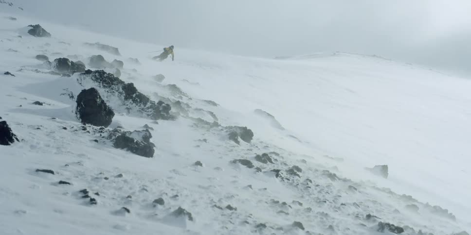 A skier on a steep windblown slope