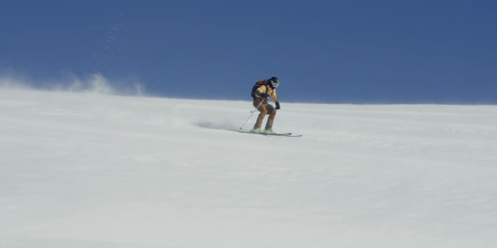 A skier makes turns down a slope