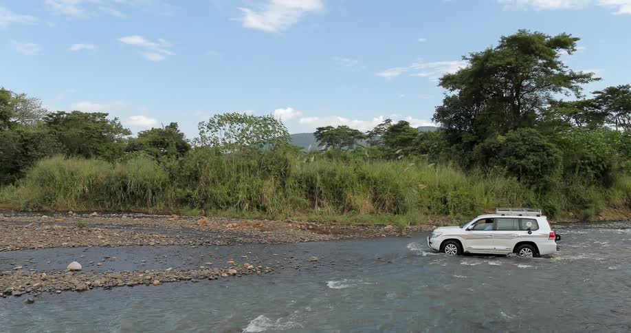 A white car drives through a river