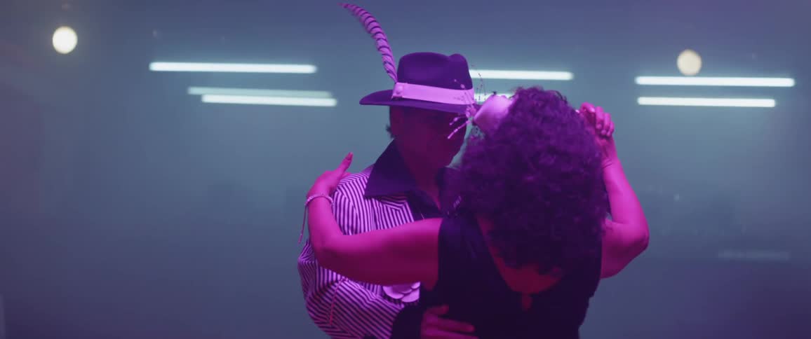 Man and woman dance illuminated by bluish light