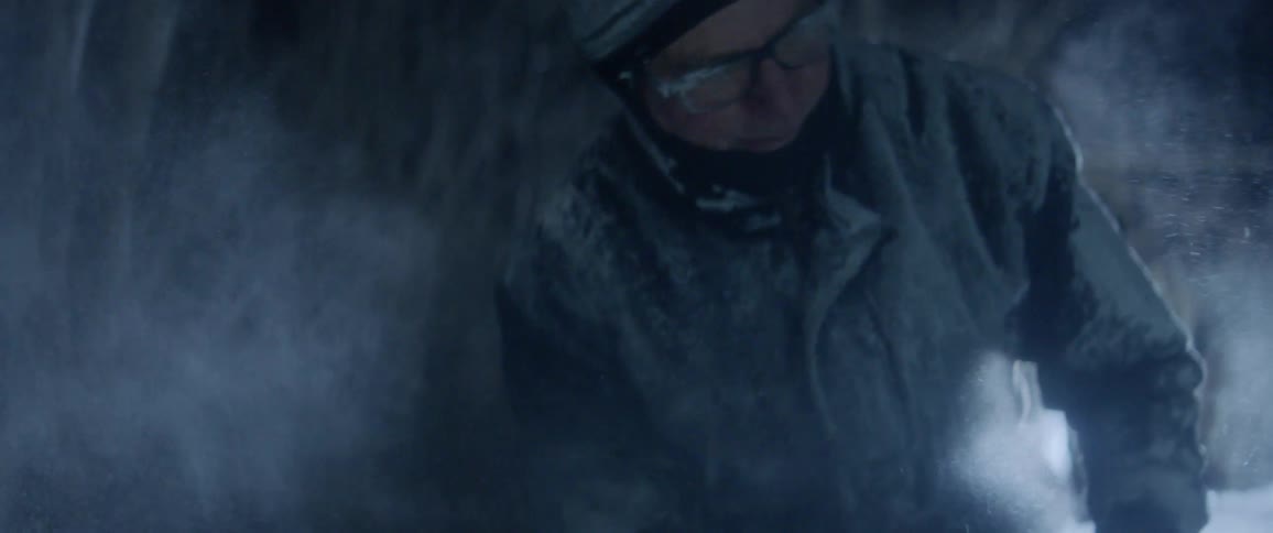 A man uses a chainsaw to shape a block of ice