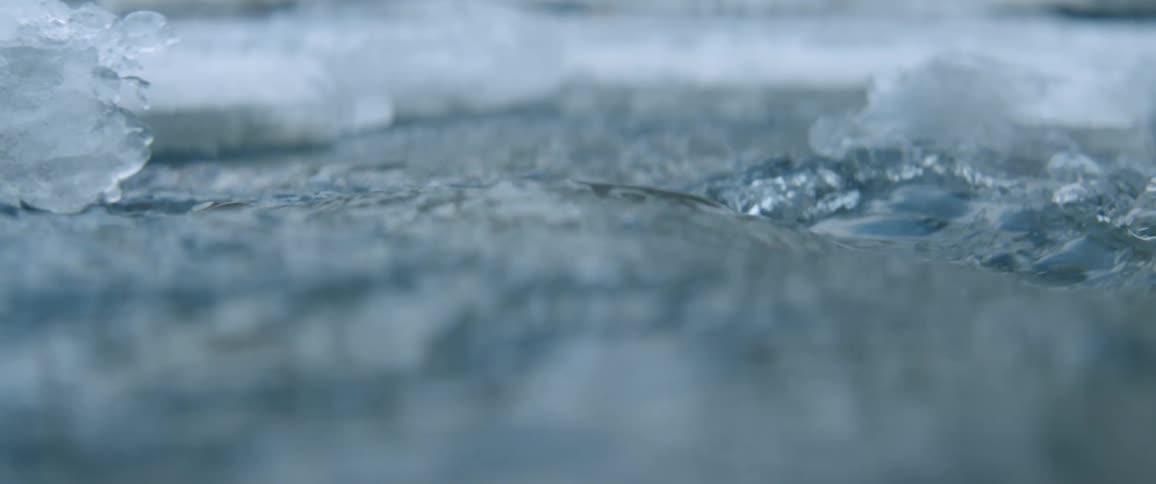 Water in a river is flowing past ice during the day