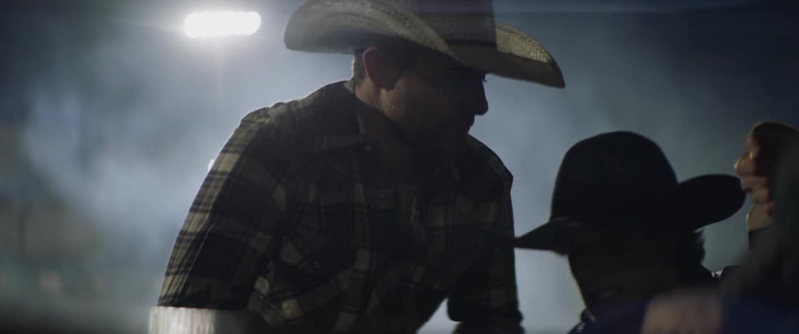 A couple of guys in cowboy hats are talking to each other while tying a rope