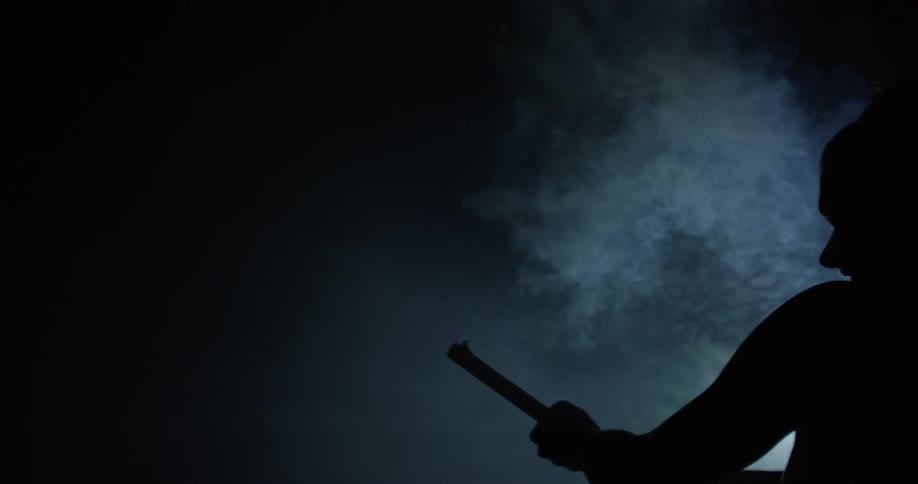 A man stands in a dark area and shoots a flare