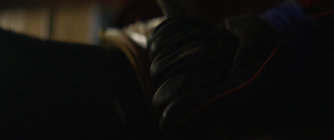 A cowboy is securing his grip on a saddle with a rope