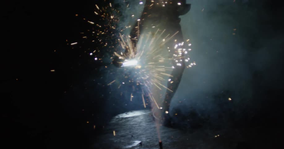 A man jumps over some fireworks exploding in the area