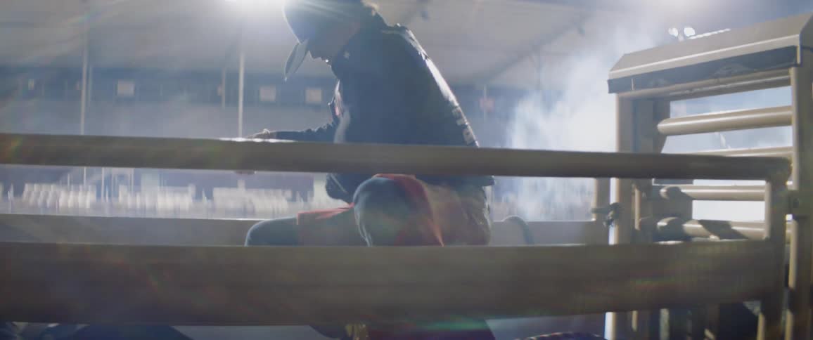 A rodeo cowboy is getting on his ride in a rodeo