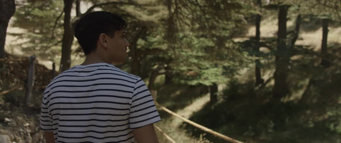 A man holding a bottle is walking along a trail