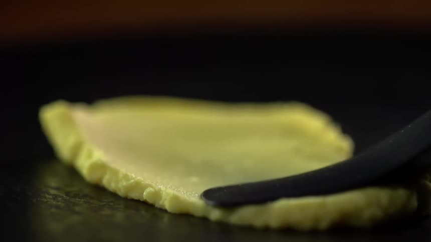 A yellow spread is moved across a black surface