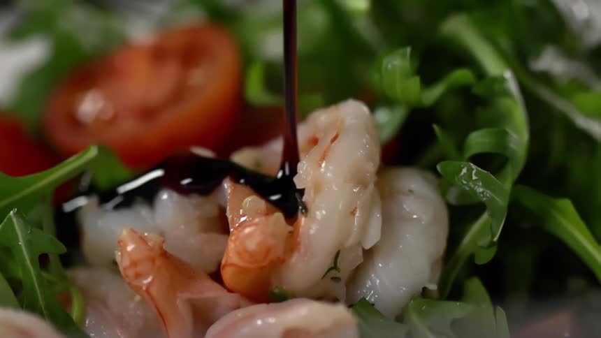 Dark thick sauce pouring over cooked shrimp in a leafy green salad