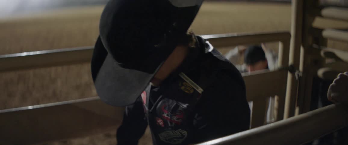 A cowboy is in a pen getting ready for his ride in a rodeo