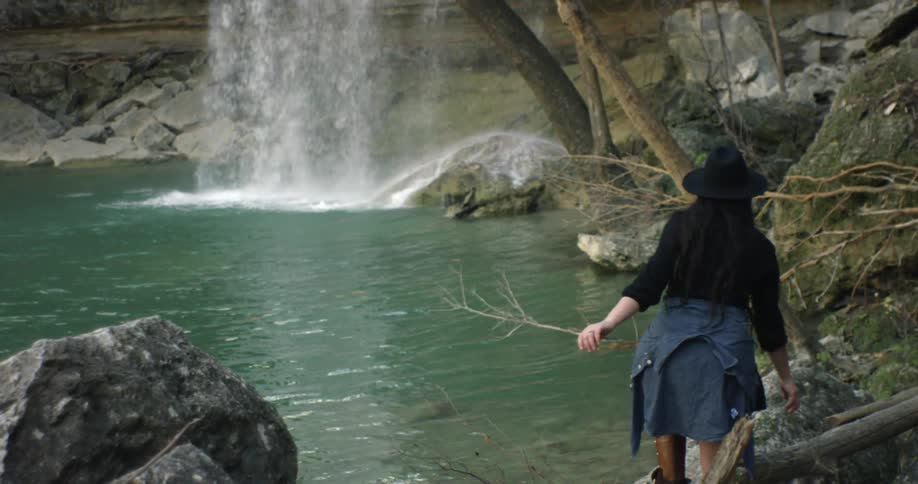 A woman walks towards a waterfall