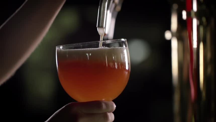A white woman fills a glass with beer