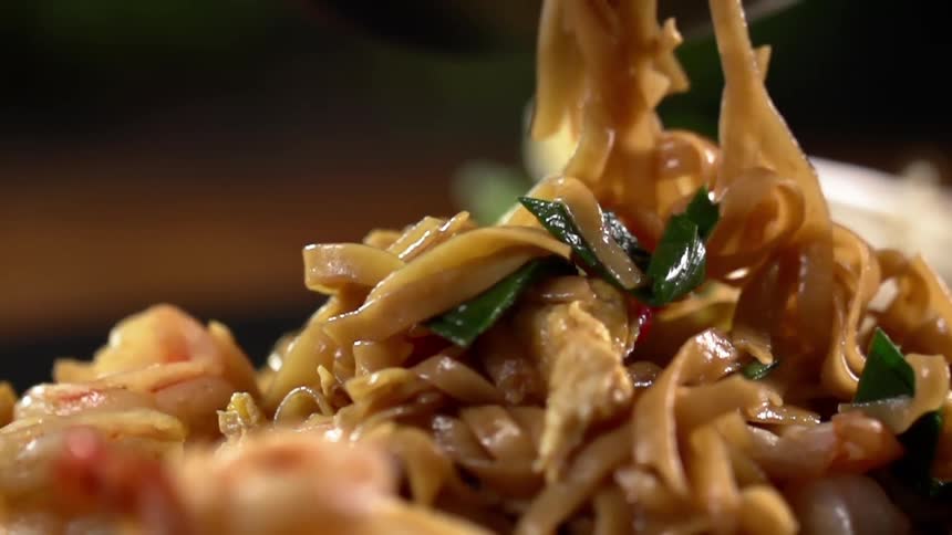 Lo mein and vegetables and shrimp being served by a spoon